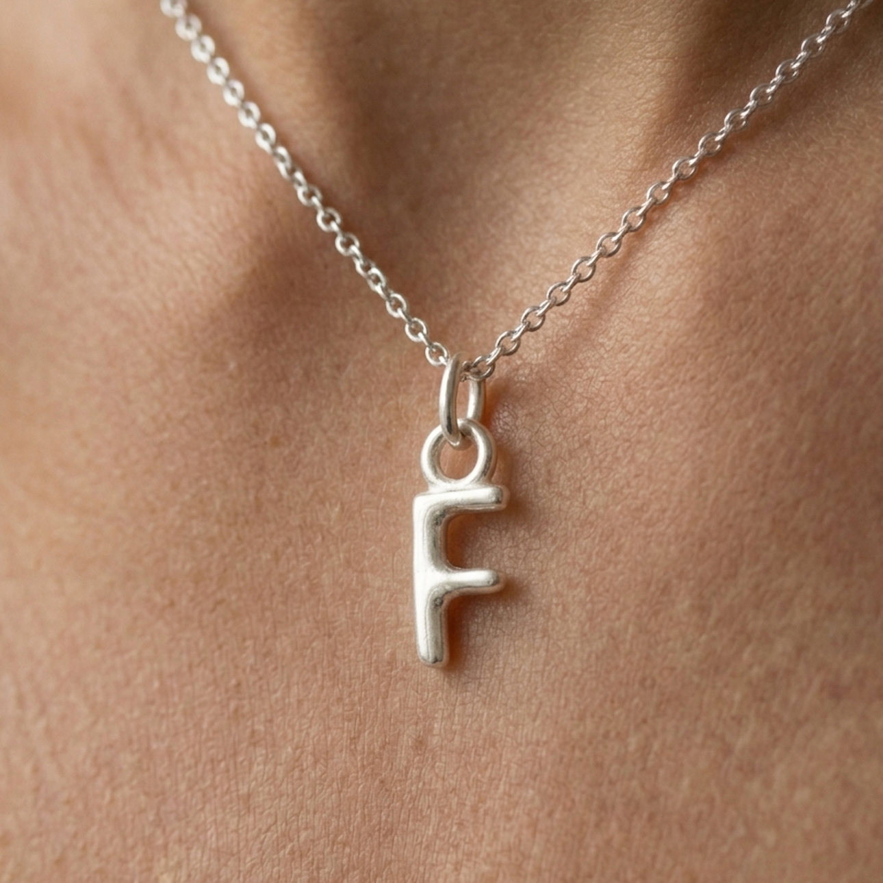 Silver necklace with a 'F' pendant on a person's neck