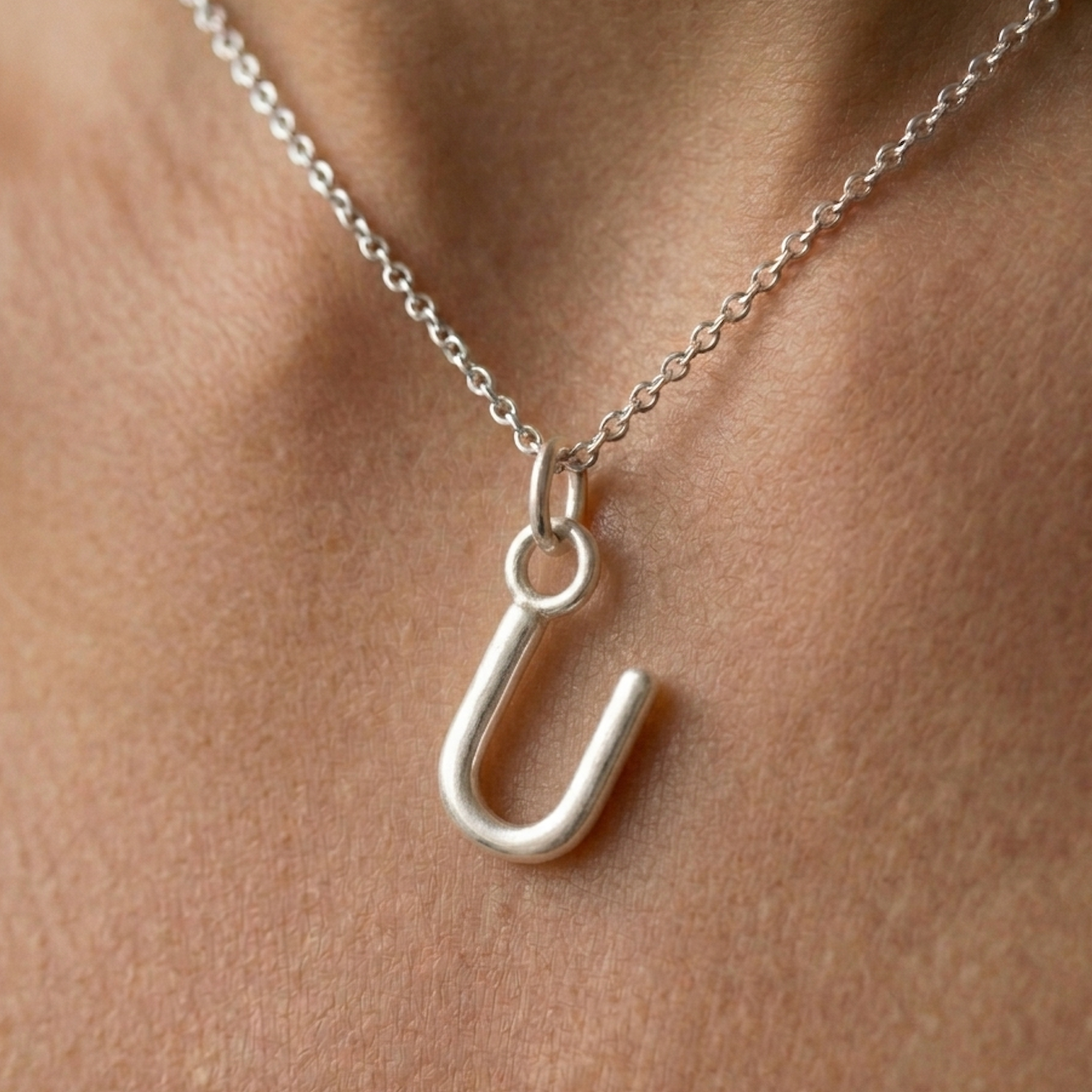 Silver necklace with a U-shaped pendant on a person's neck
