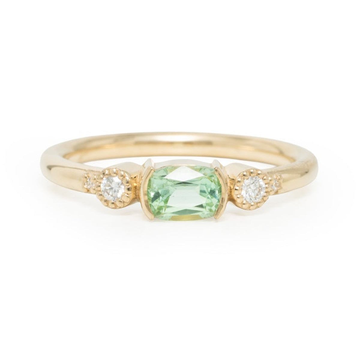 Tula ring with a 0.50 ct cushion-cut green tourmaline set in yellow gold, on a white background
