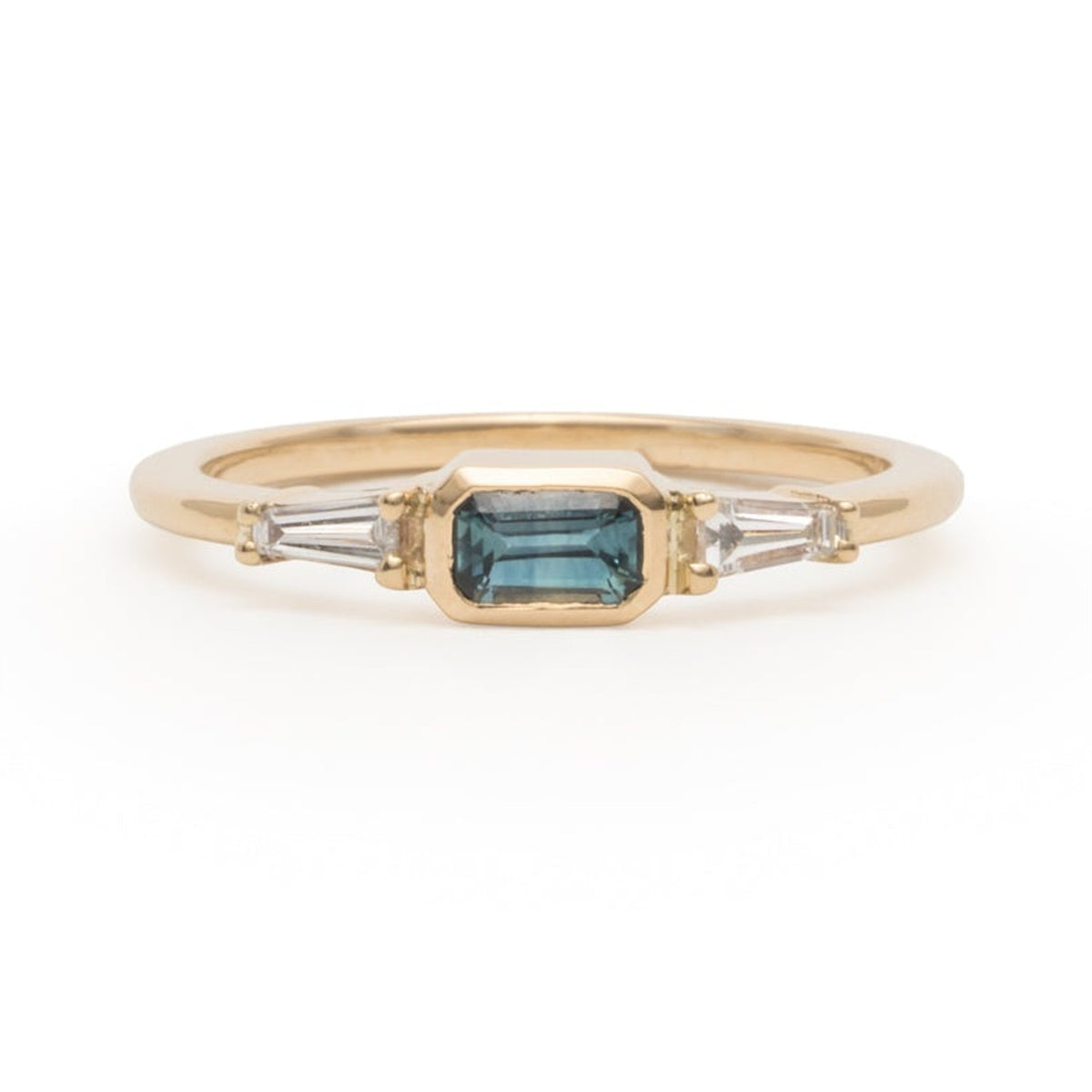 Lupin ring with an emerald-cut blue sapphire and baguette diamonds in yellow gold, on a white background