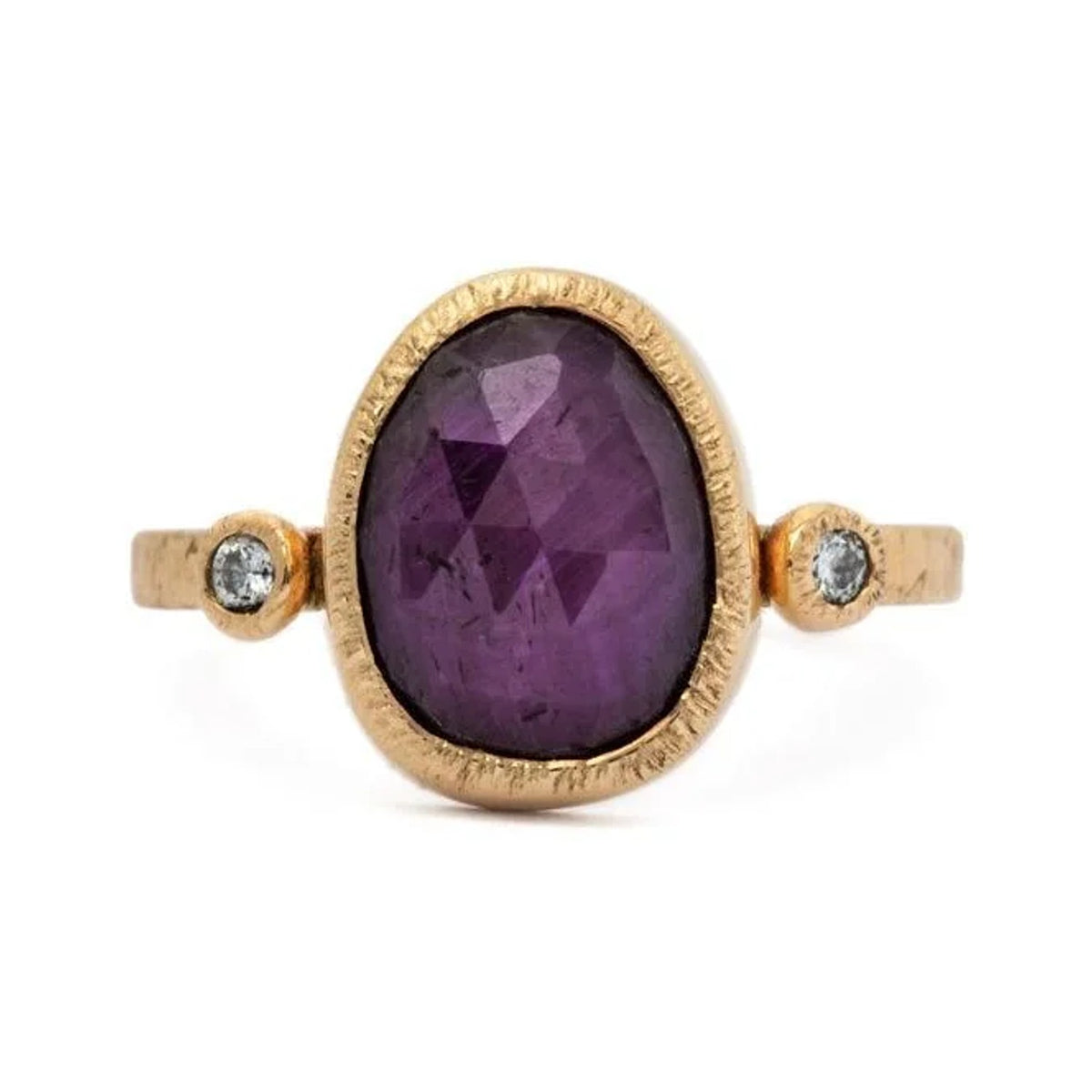 Ruby custom ring with an oval purple-red ruby and two small diamonds in textured 14k gold