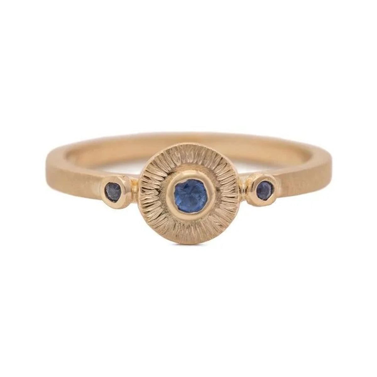 Solaris sapphire ring in 14k gold with a blue centre stone in a textured sunburst disc, front view