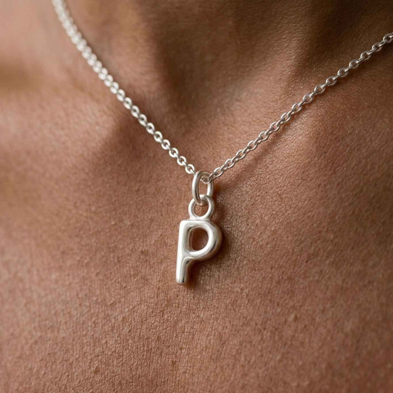 Silver necklace with a 'P' pendant on a person's neck