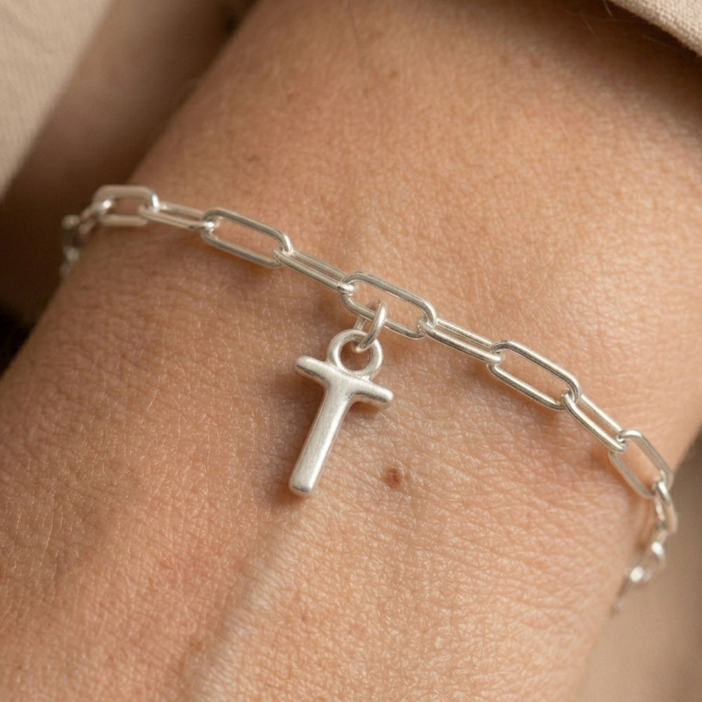Silver chain bracelet with a T charm on a wrist.