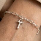 Silver chain bracelet with a T charm on a wrist.