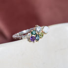 Cathy mixed metal cluster ring with colourful gemstones and an opal on white ceramic, burgundy backdrop