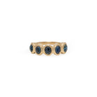 Gold ring with five blue sapphire gemstones on a white background