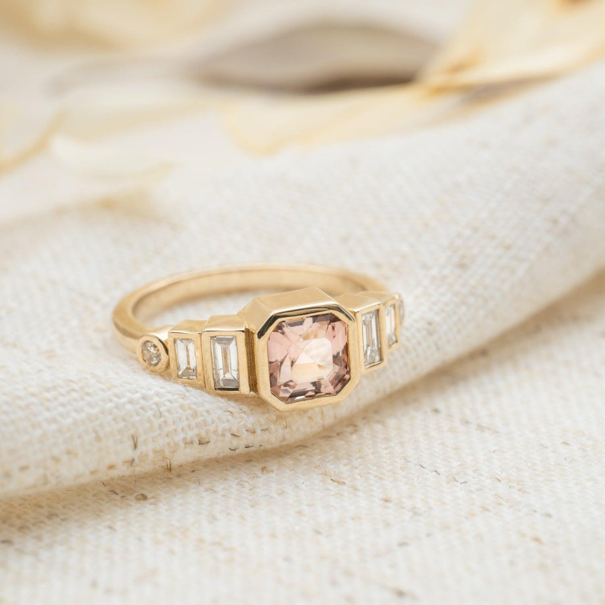Rwanda pink tourmaline and diamond ring in 14k gold resting on cream linen