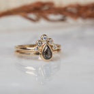 Peri pear salt and pepper diamond ring stacked with a gold crown band of five white stones on marble